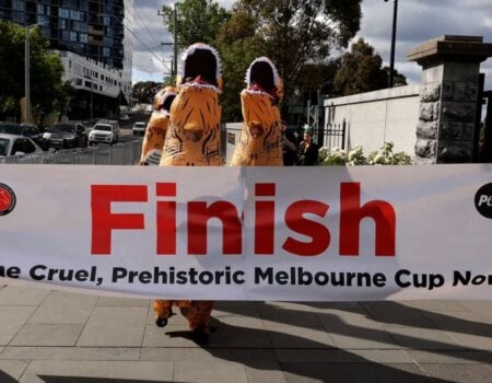 dinosaurs cross the fish line. Banner reads: Finish the Cruel, Prehistoric Melbourne Cup