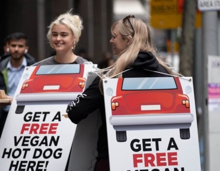 Stefania and Stace wear signs reading: Free Hot Dogs from Cars and Get a Free Vegan Hot Dog Here