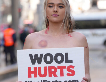 Tash Peterson holds a sign reading "Wool Hurts" WoolFacts.com